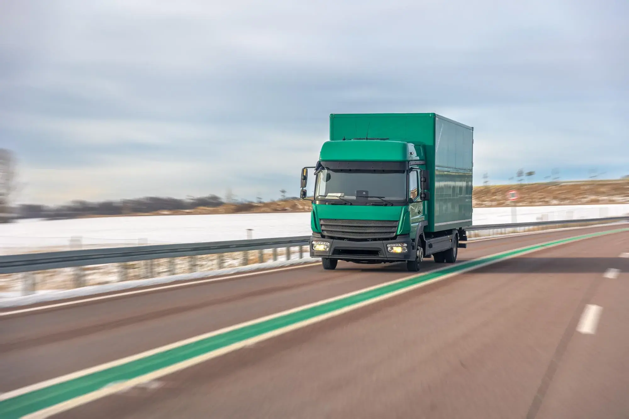 A lorry running along an open road, the roadside blurred by its speed